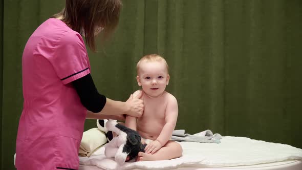 The masseuse gives a massage of shoulder to baby (boy) 05 alt