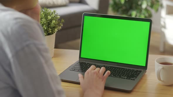 Closeup On the Hands of the Female Specialist Works on a Laptop Computer with Mockup Green Screen alt