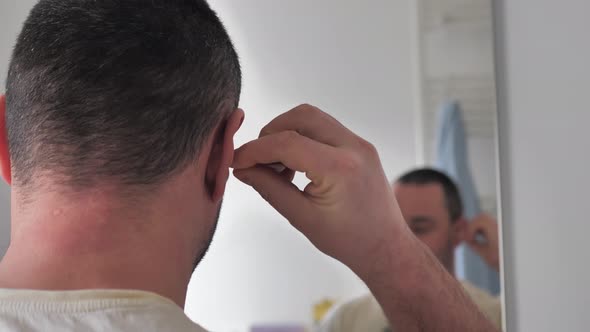 A Man Cleans His Ears in the Bathroom alt