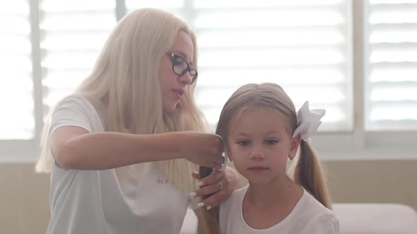 Mom Combs Hair to a Little Girl with Blue Eyes Slow Motion