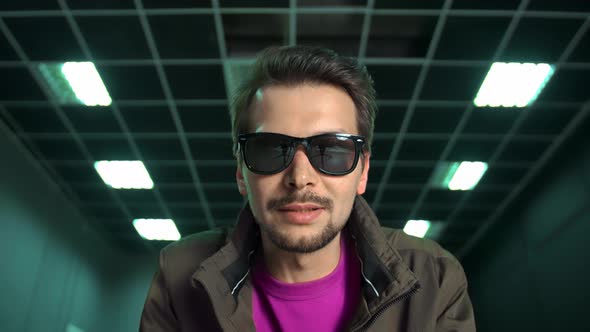 Man in Sunglasses Sits Down in Front of Camera Says Something