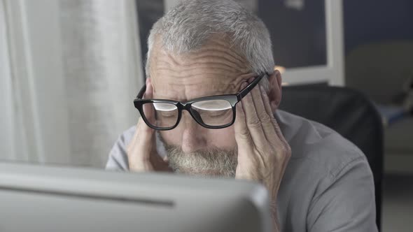 Senior man working with computer and feeling tired