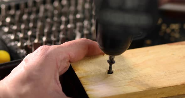 Close up of man hand drilling into wood self-tapping screw twisted into place