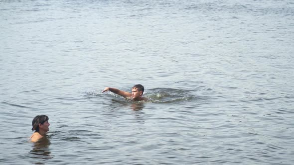 Teenager Swims In the Lake Next To His Mother