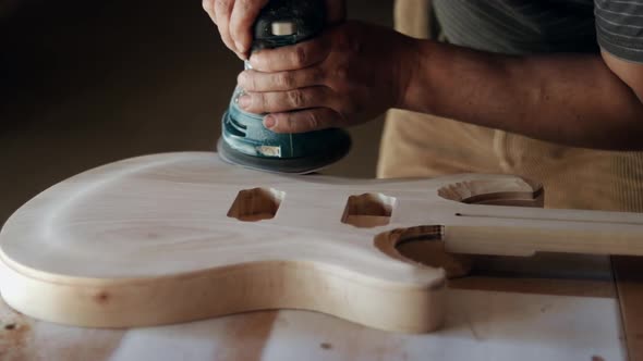 Craftsman grinds wood while making a guitar