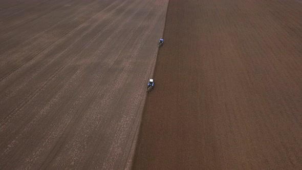 Agricultural Work in the Field, Two Blue Tractors Plow the Land