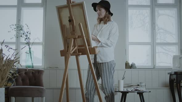 Woman Artist Paints At An Easel alt