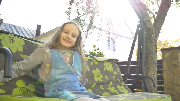 Little Child Blond Girl Having Fun on a Swing Outdoor During Summer Sunny Day on Playground in the alt