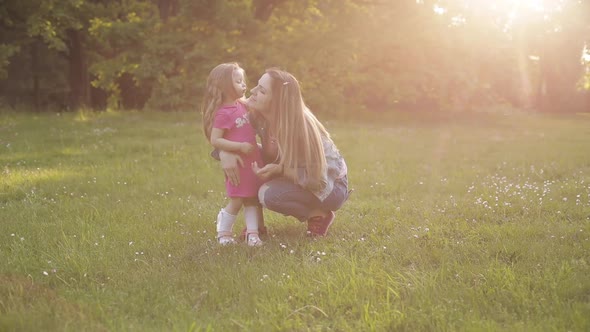 Little Kid with Long Hair Sitting on Front of Her Mother