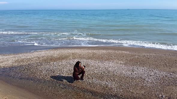 Beautiful girl takes pictures on the ocean. View from the drone girl makes a video.