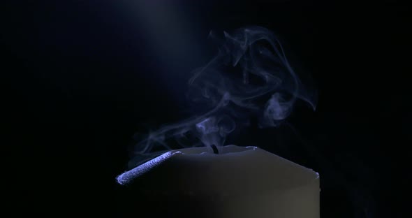 Slow motion close up footage of a white candle on a dark background alt