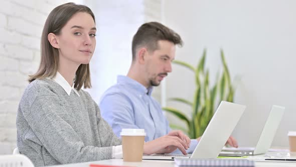 Beautiful Creative Woman Working on Laptop and Smiling at the Camera alt