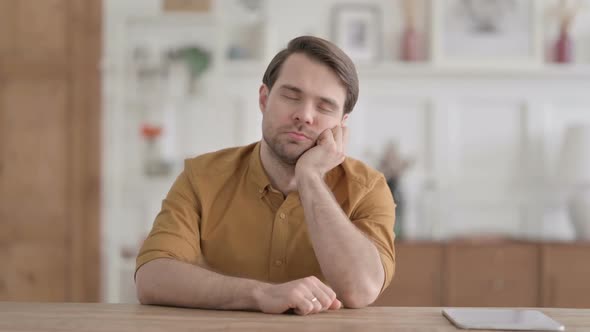 Sleepy Young Man Taking Nap While Sitting in Office alt