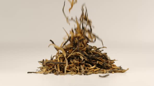 Tea leaves fall on a pile of a black tea