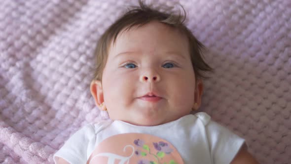 Slow Motion of Beautiful Baby with Blue Eyes Looking at Camera alt