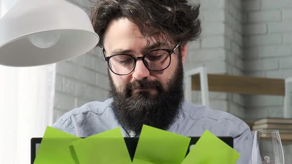 Bearded Man That Works at the Computer Full of Reminder Notes Home Office alt