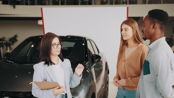 Female Seller Working with Multiracial Couple at Modern Auto Center alt