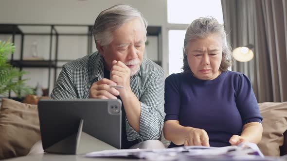 old retired asian senior couple checking and calculate financial billing together