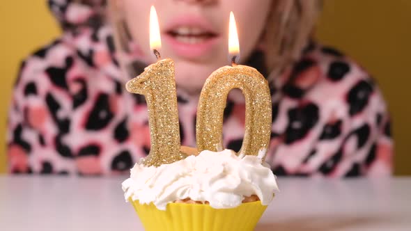 Happy Teen Girl in Leopard Overalls Blows Out Number 10 Candle on Birthday Cake at Party