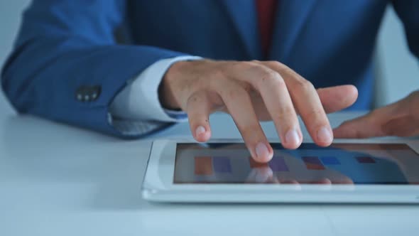 Businessman Using Tablet Device with Business Report