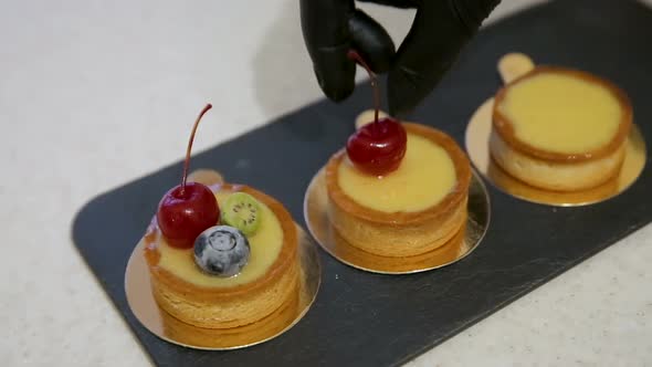 Close up of chef decorating a fresh baked cake with cherry and blueberry alt