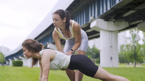Woman Does Plank with Friend on Fresh Meadow