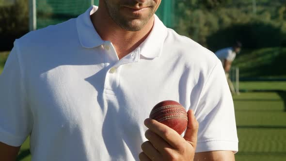 Confident cricket player holding ball during a practice session alt