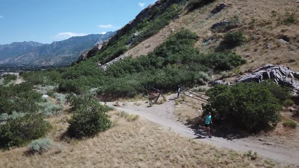 Drone Shot following an active man running on the outdoor Wasatch Mountain trails above Draper City, alt