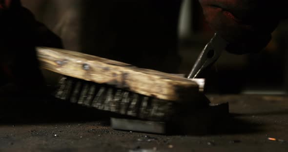 Hands of welder using wire brush on a piece of metal alt
