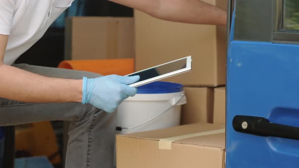 Delivery Man with a Tablet Checks His Cargo Count, Closeup