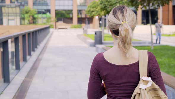 Following Woman with Backpack Walks Along Park