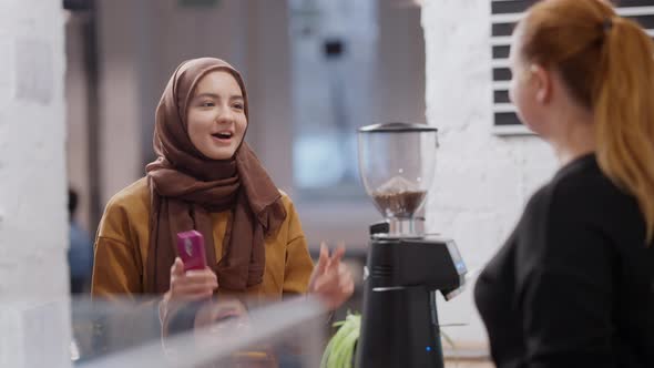 Positive Young Beautiful Muslim Woman Making Order in Coffee House alt