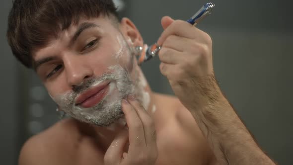 Closeup Front View Man Shaving Cheek Smiling in Slow Motion alt