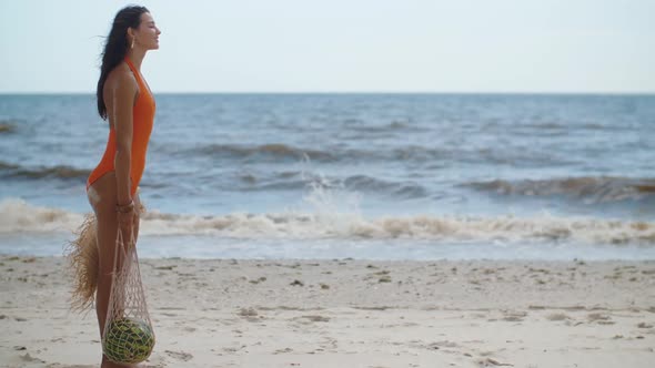 Woman in Swimsuit with Watermelon on the Beach Outdoors alt