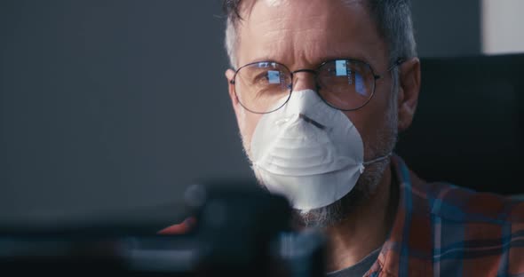 Man in Face Mask Having Video Call alt