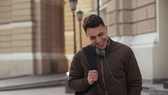 Portrait of European Joyful Guy 20s with Backpack Behind His Back Laughing Out Loud While Strolling alt