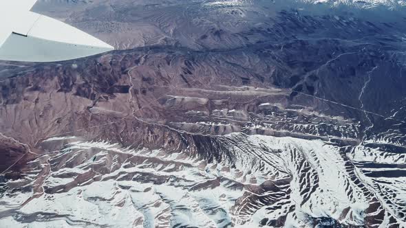 Airplane Flying Over Beautiful Mountainous Terrain Covered Partly in Snow alt