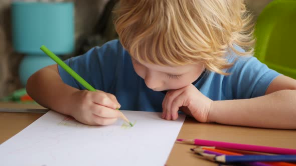 4-year Blonde Boy Drawing with Colored Pencils.