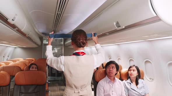 Back view. Airline flight attendant demonstrating a seat belt before takeoff.