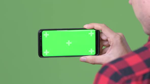 Young Scandinavian Businessman Using Mobile Phone Against Green Background alt