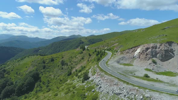 Car Driving Along the Empty Gravel Road Through Green Meadows Landscape on Sunny and Warm Day alt