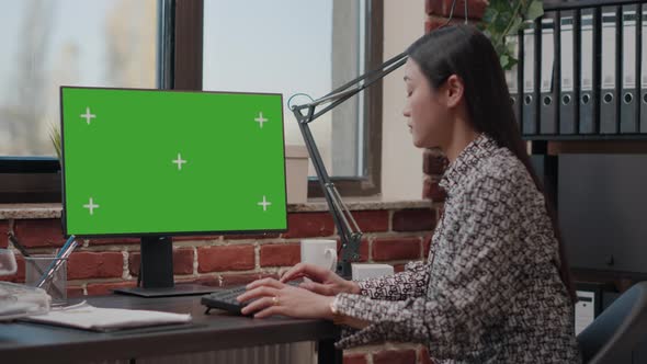 Asian Woman Working on Monitor with Horizontal Green Screen alt