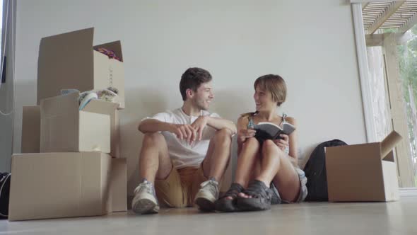 Couple sitting on floor amongst cardboard boxes alt