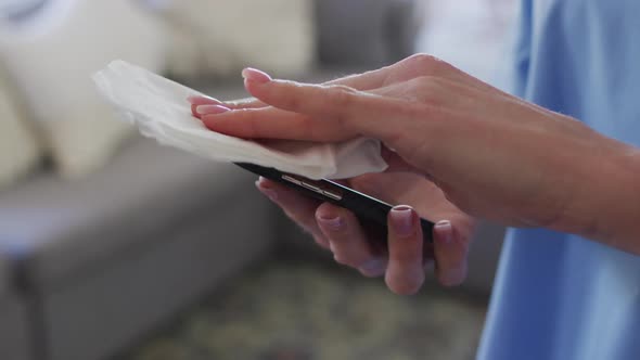 Mid section of Female health worker wiping her smartphone with a tissue alt