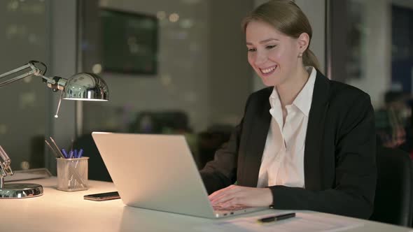 Ambitious Businesswoman Doing Video Chat on Laptop at Night alt