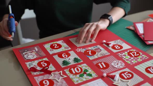Closeup of Unrecognizable Young Woman Gluing Envelopes with Gifts for Children Making Christmas alt