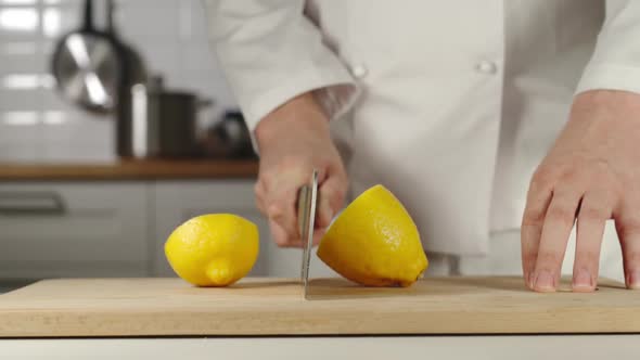 Chef Chopping A Whole Fresh Lemon On Wooden Board While Cooking