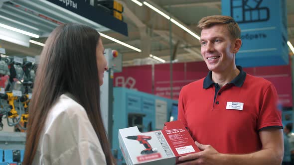 Sales assistant in the building tools department talking to a female customer about a product