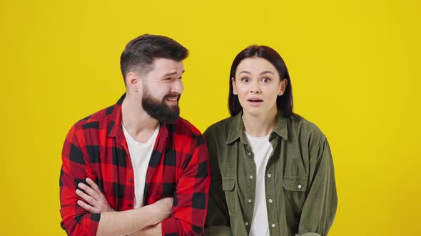 Portrait of Shocked Couple Against Yellow Background alt