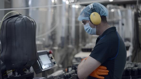 Factory Worker Operating Conveyor With Beer Cans Moving  Medium Shot alt